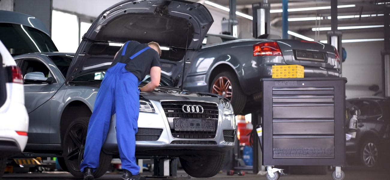 Grey Audi dans un garage HELLA Service Partner pour réparation.